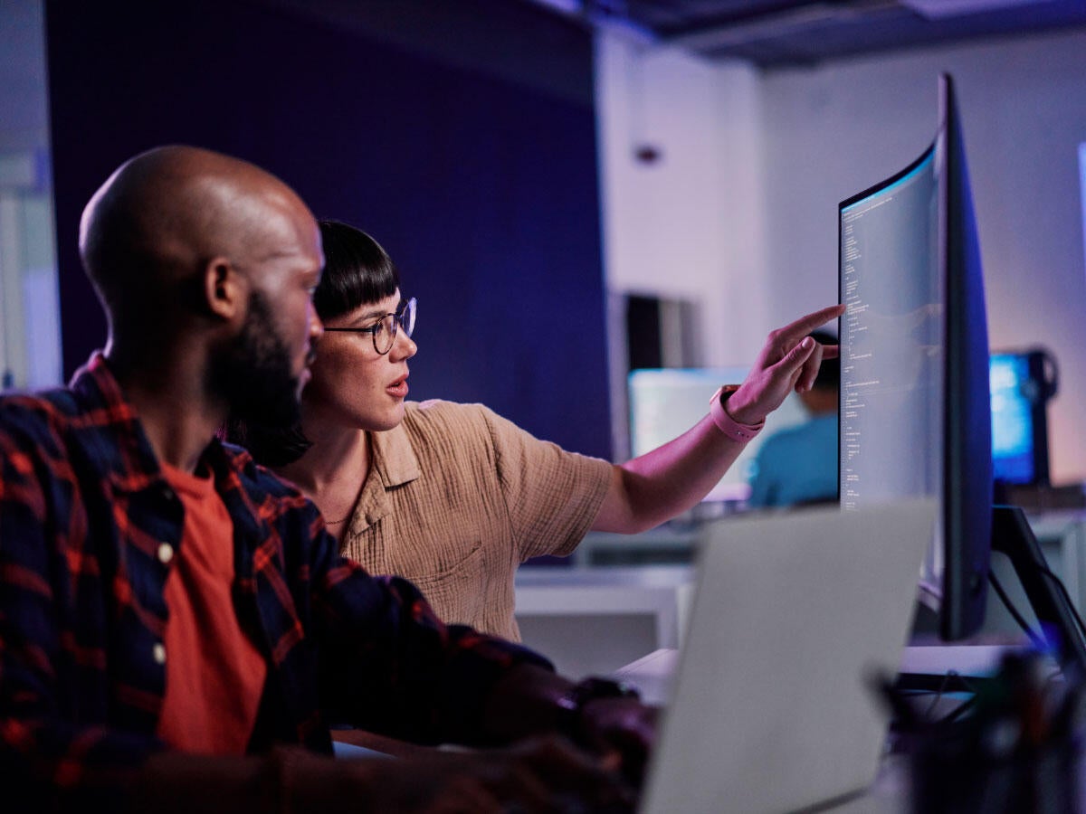 Two developers working together to review software code on a computer
