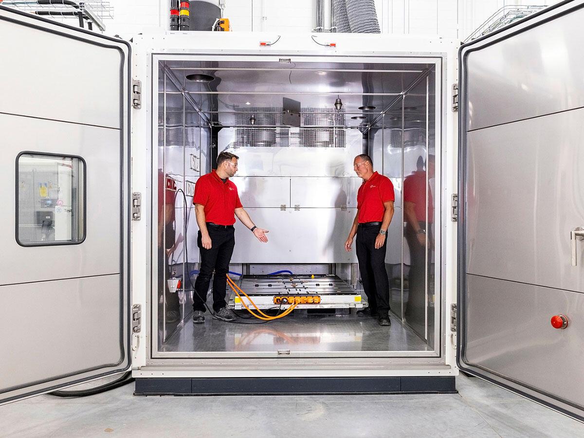 Engineers working inside the performance test chamber with a battery pack placed inside