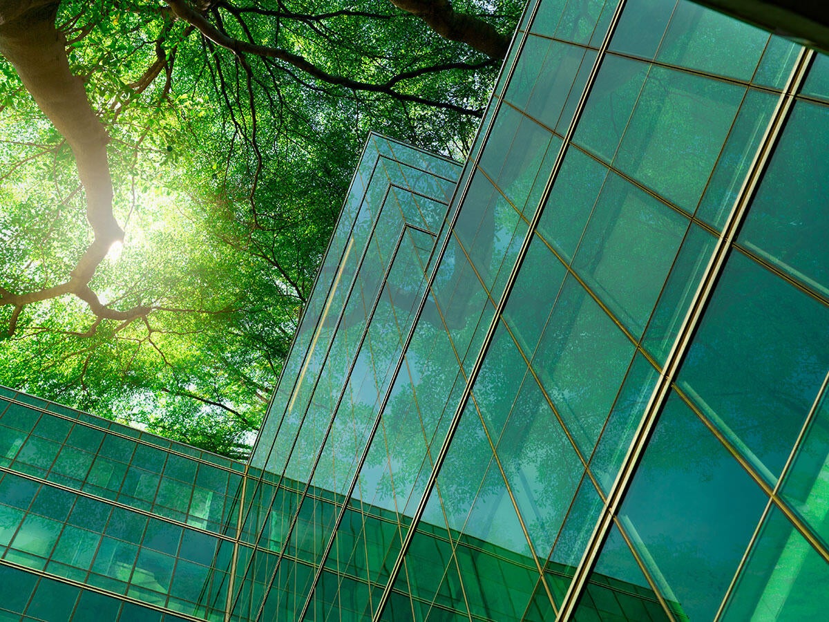 a green glass office building with trees in courtyard