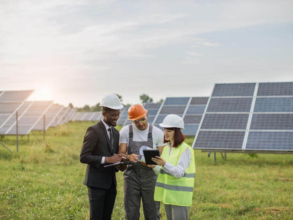Workers talking near solar panels.