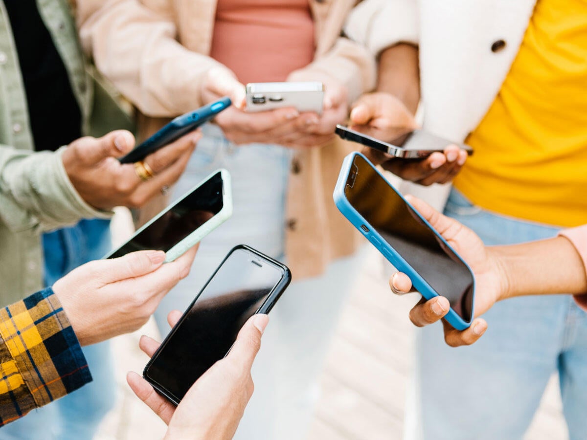 Group of people standing in a circle holding out their mobile phones