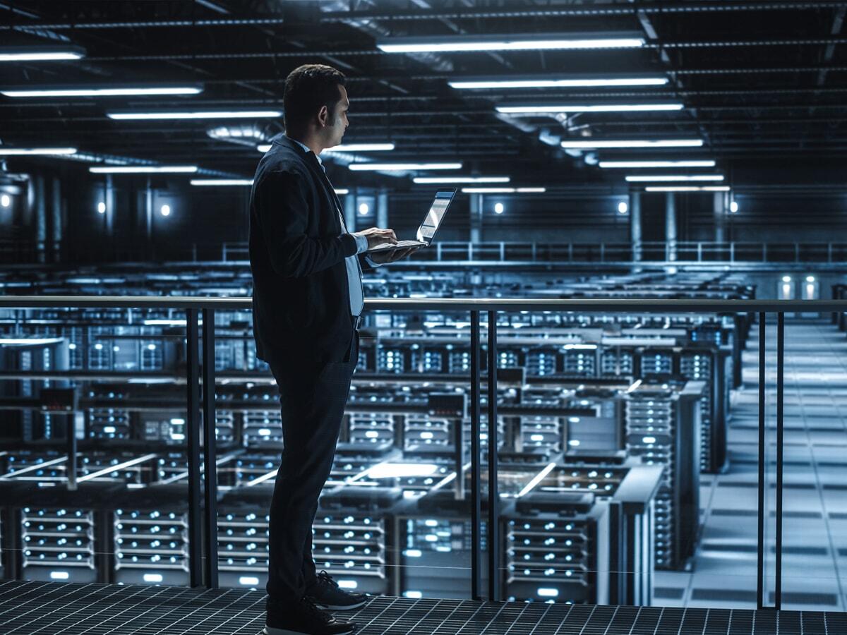 guy standing in data center and looking at laptop