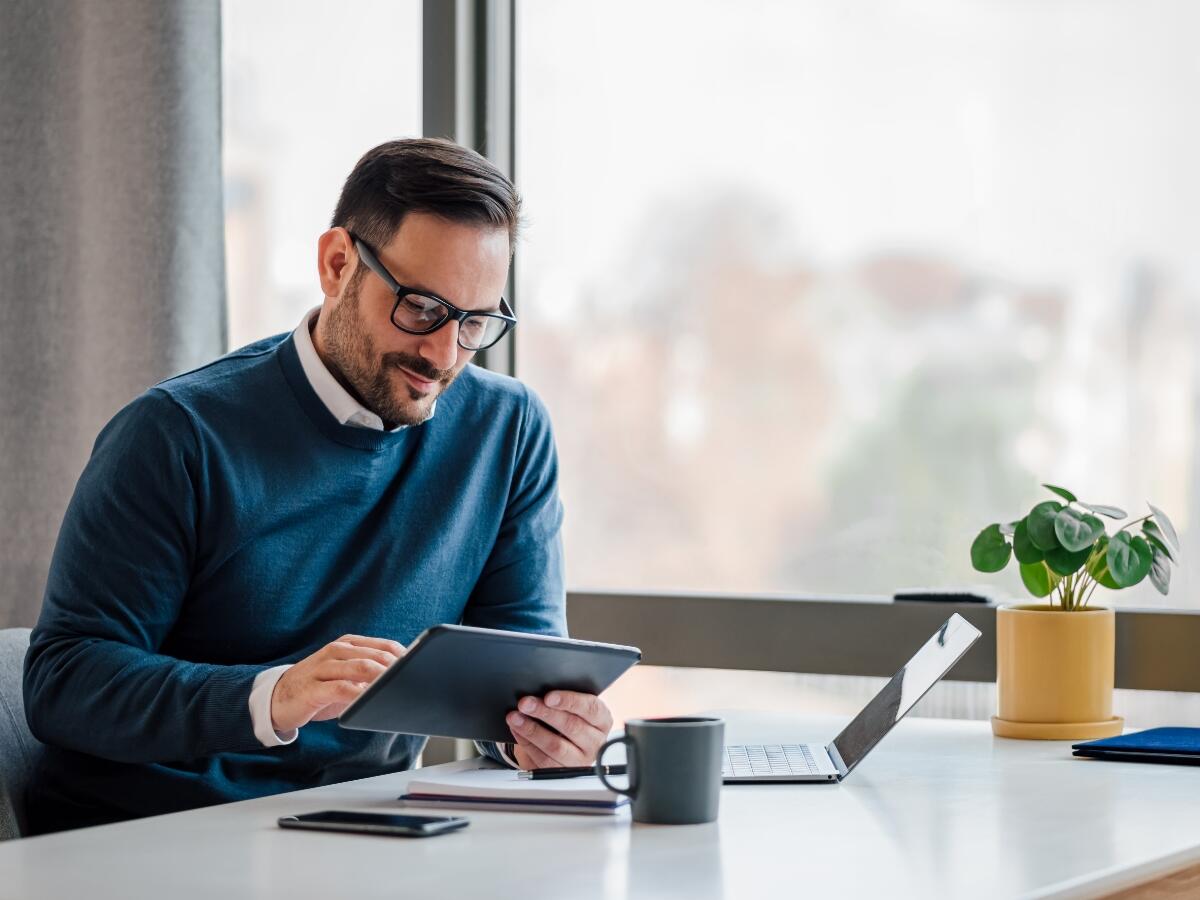 man using tablet at desk by window