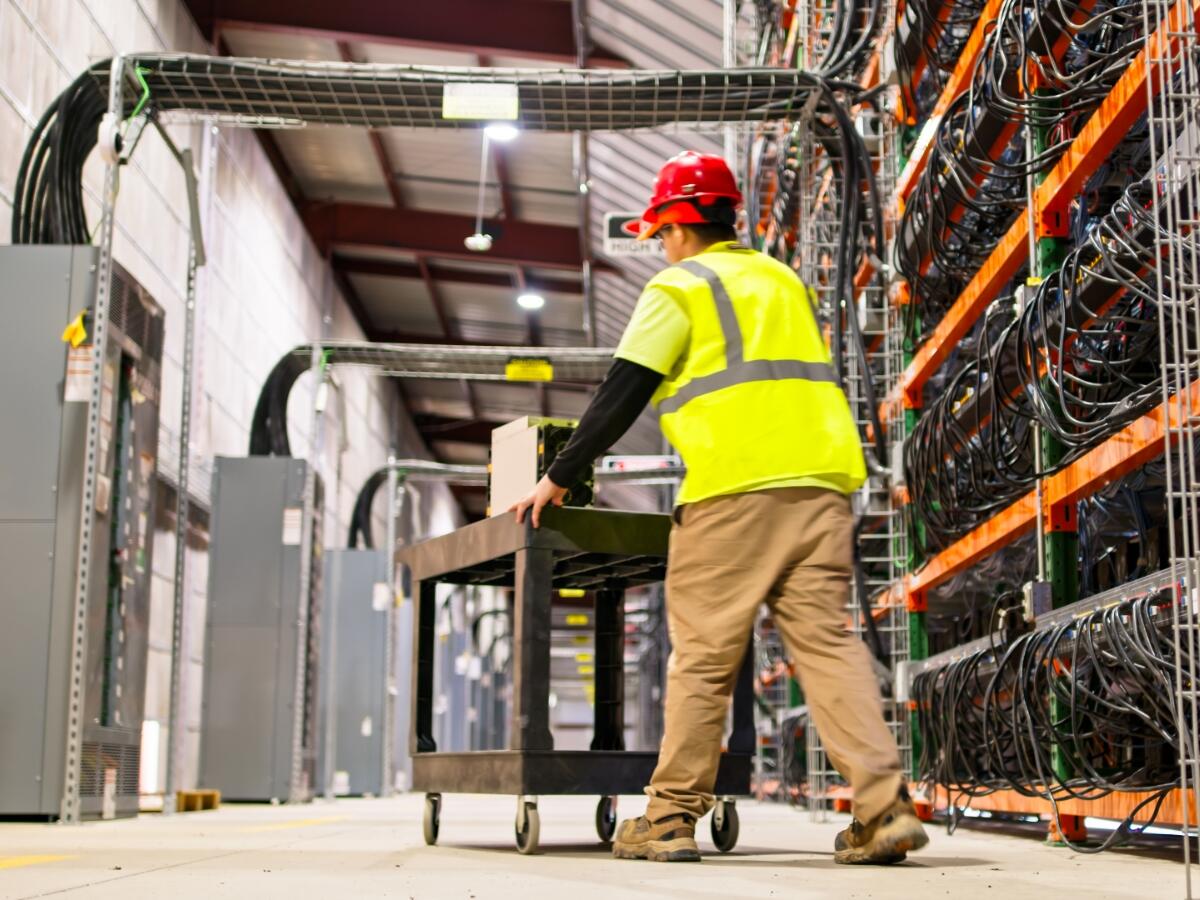 A technician pushing a cart in a massive data center