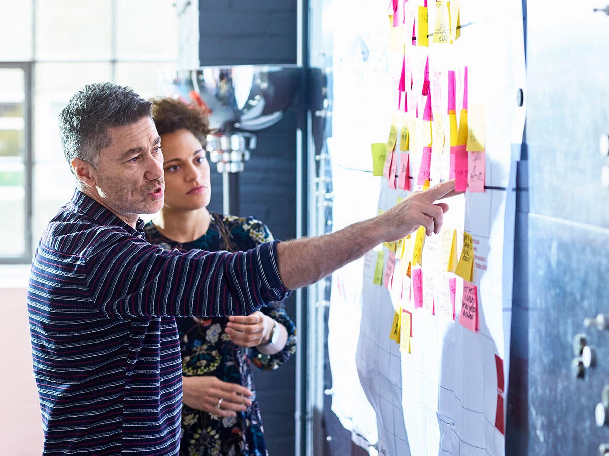 A teacher and a student using sticky notes on a white board