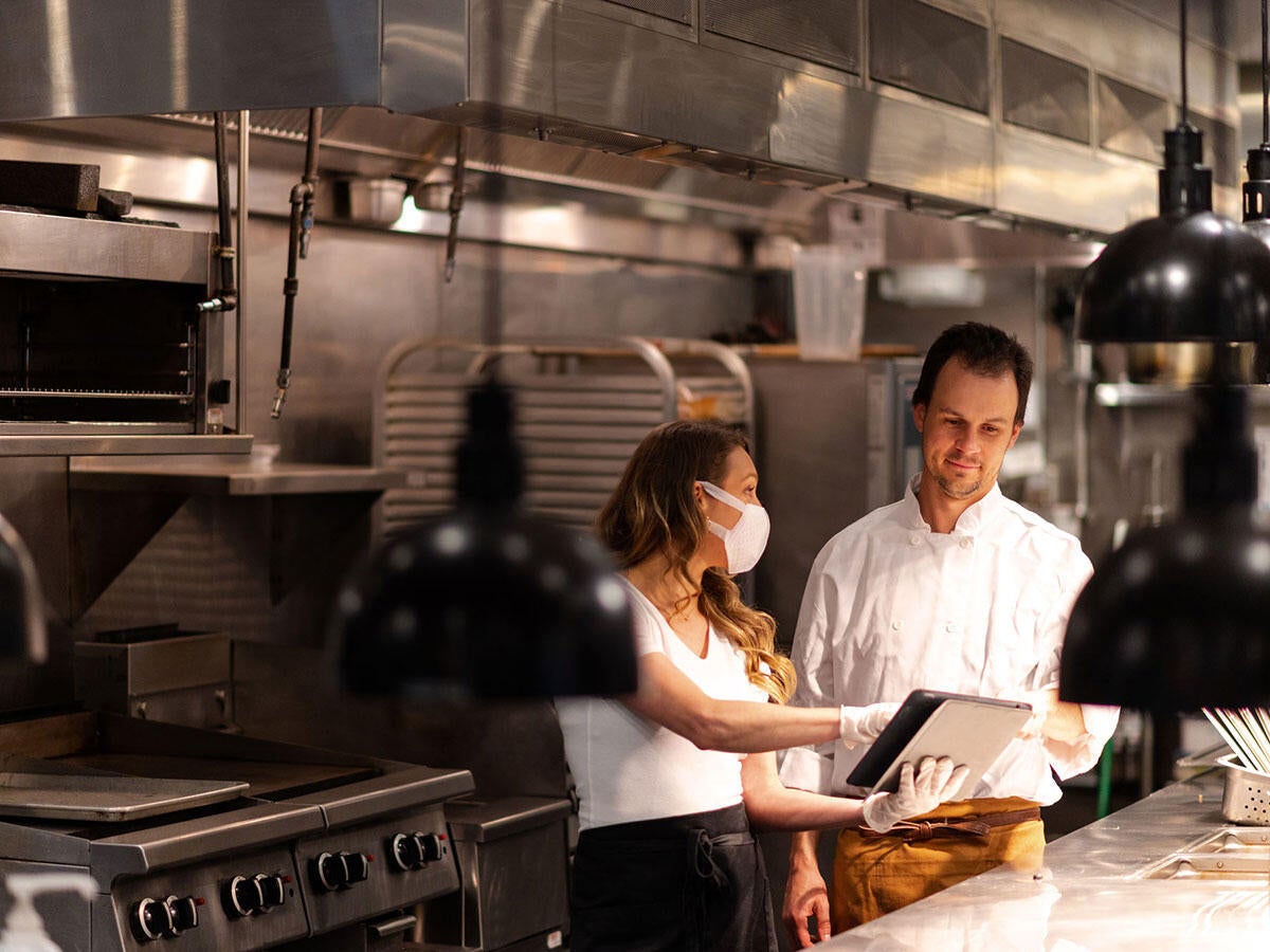 Two people working on a tablet while in a restaurant kitchen