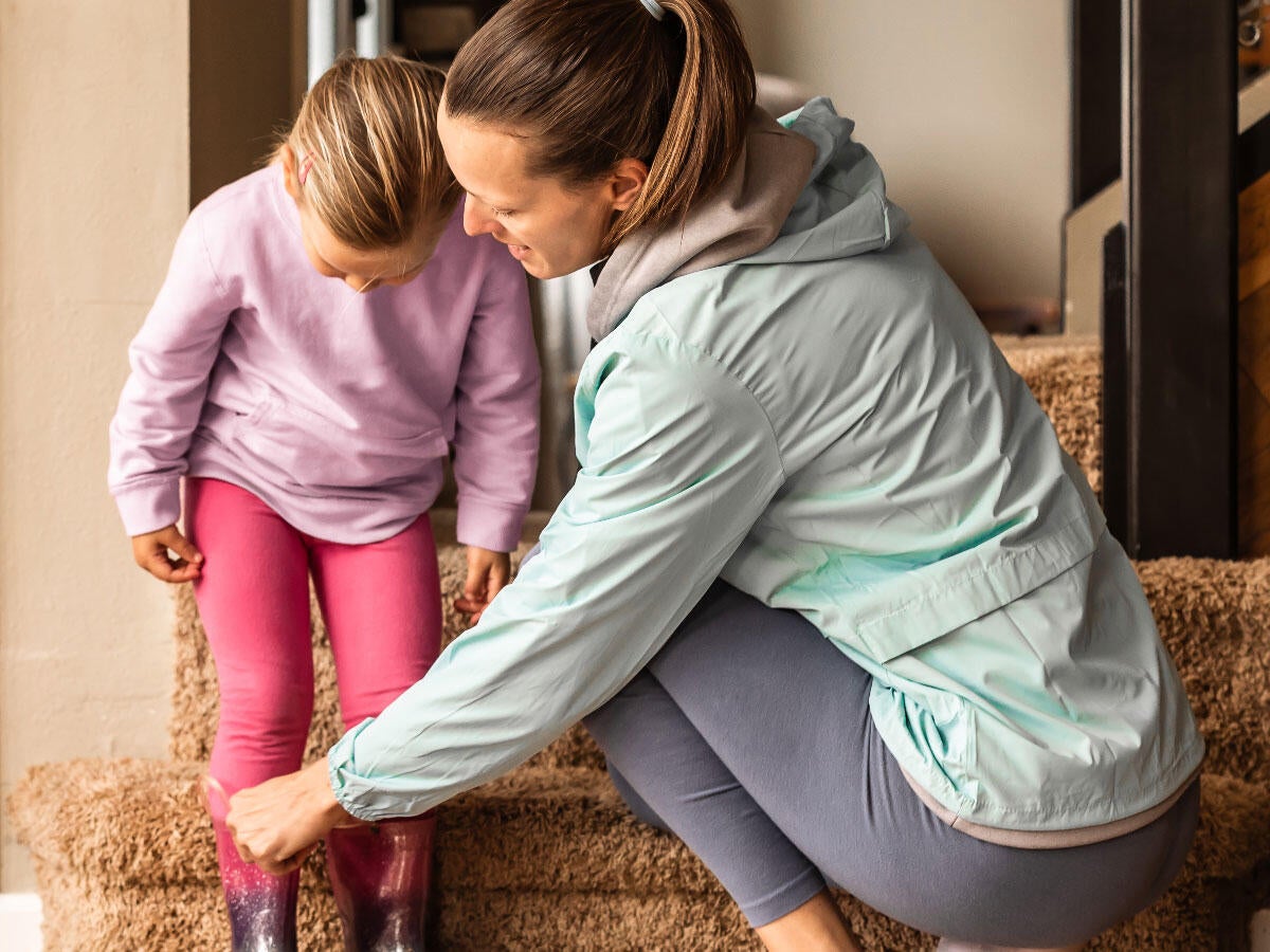 A parent helping a child put on boots