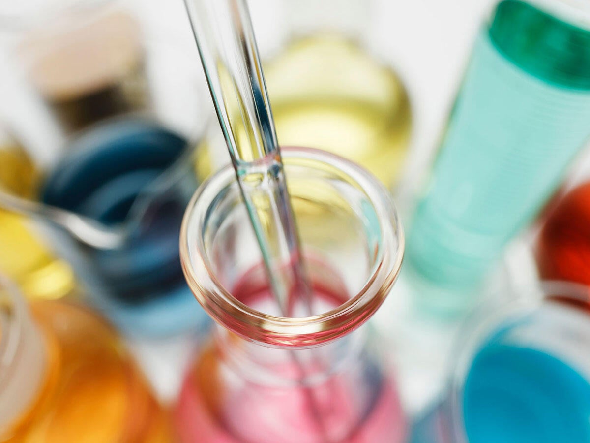 Pipette in laboratory flask containing transition metal salts