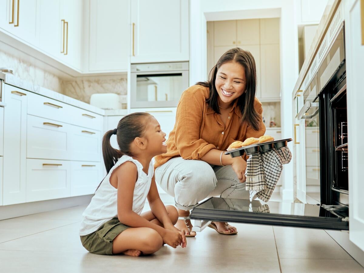 A parent and child looking at each other near an open oven