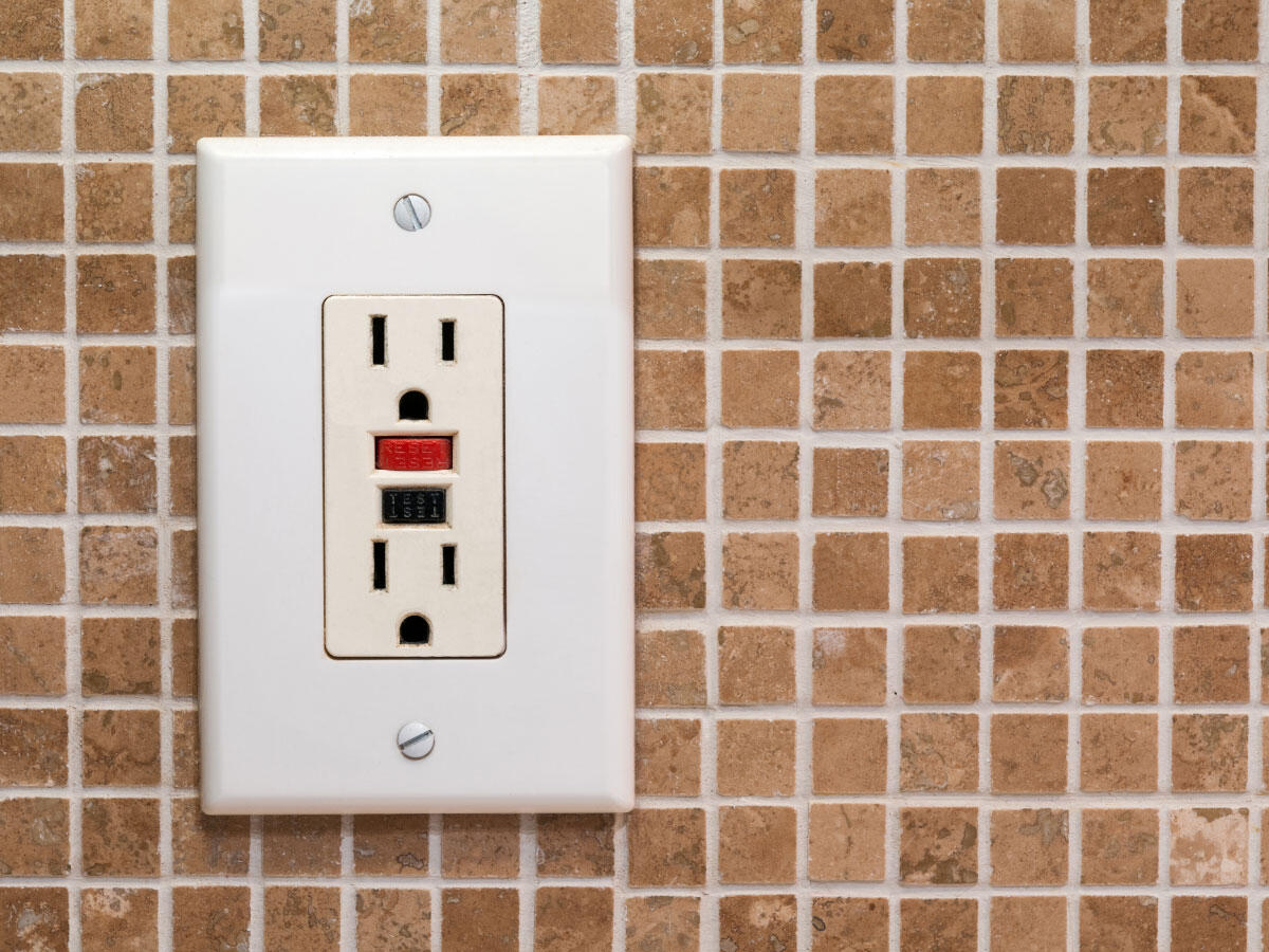 GFCI outlet installed on a tile wall background