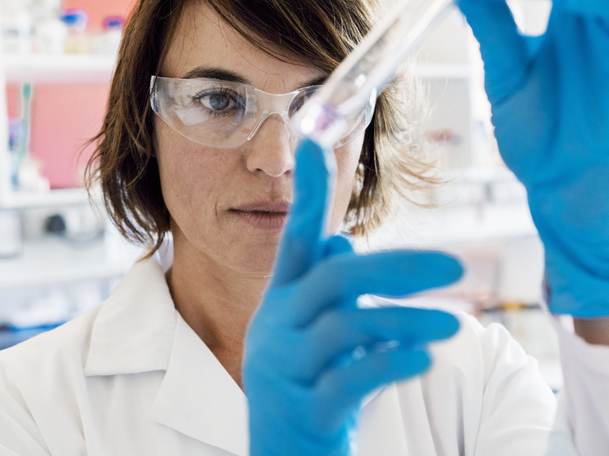 Female scientist in protective gear inspecting a liquid-filled test tube