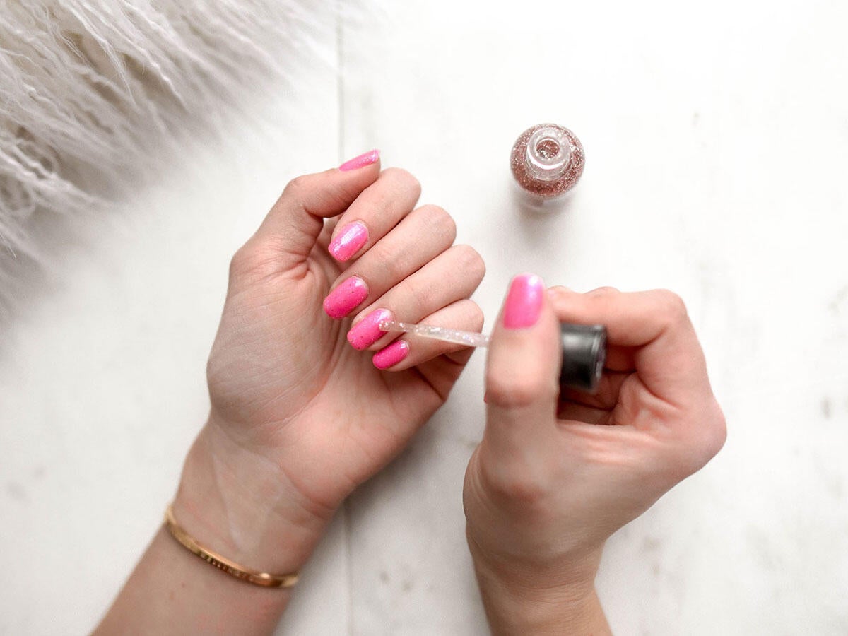 A person applying pink nail polish