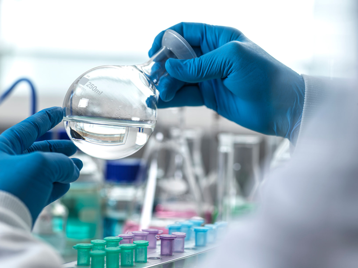 Gloved hands holding a round flask