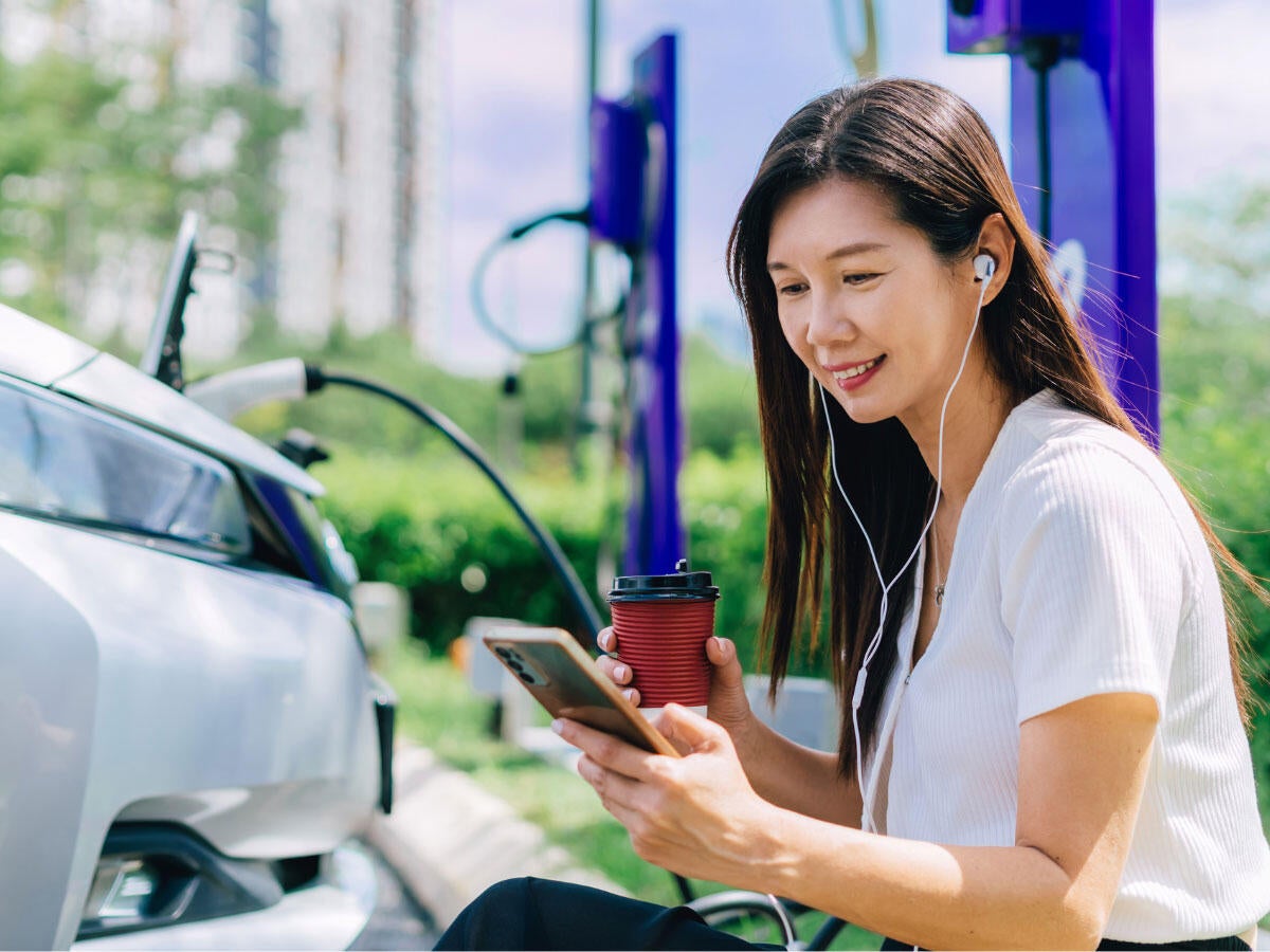 A person looking at a cellphone and wearing earbuds