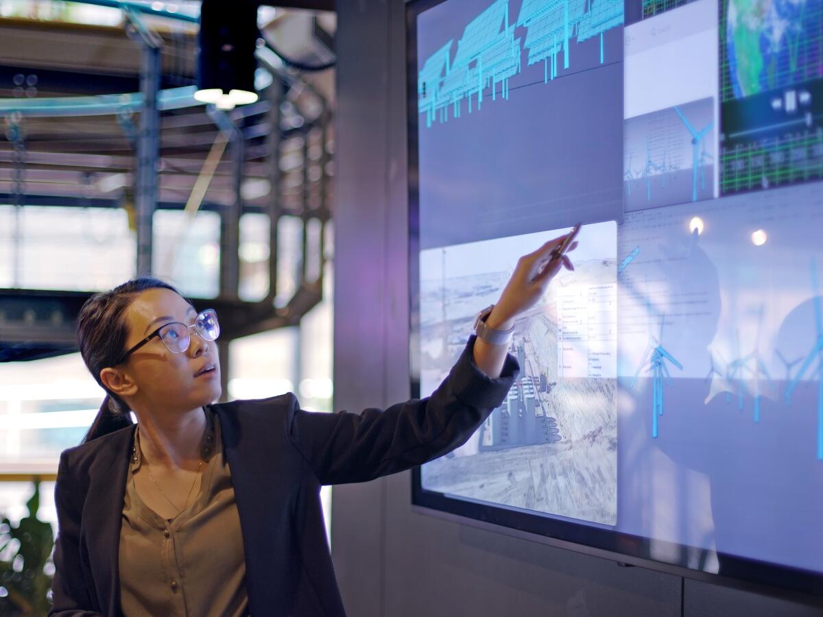 professional woman in an office gesturing at screen displaying 3d modelled windmills