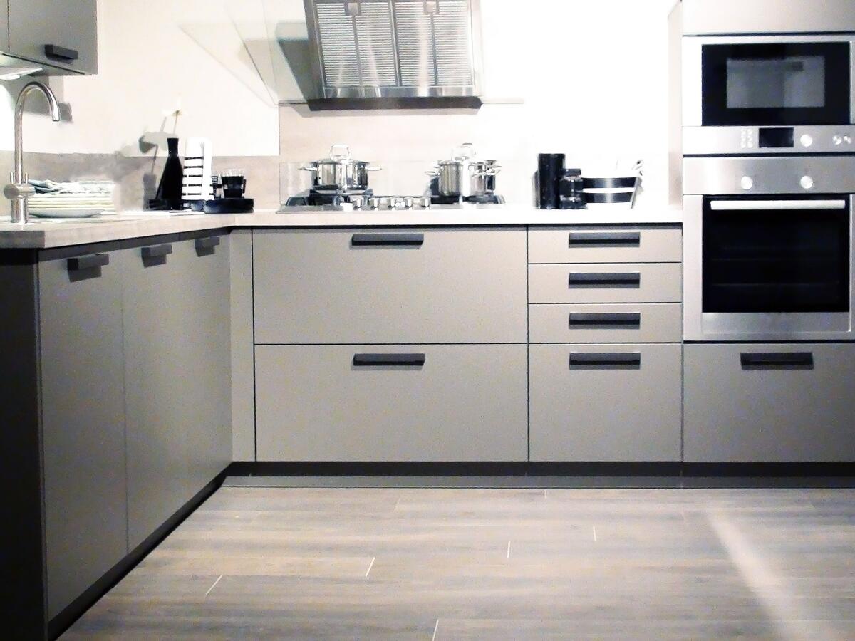 Modern kitchen with grey cabinets, stainless‑steel appliances, and a stovetop with pots.