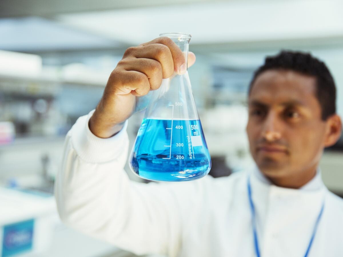 Scientist inspecting blue liquid in a flask