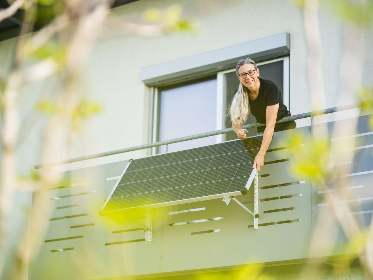 A person using a fold-up solar panel on their deck wall