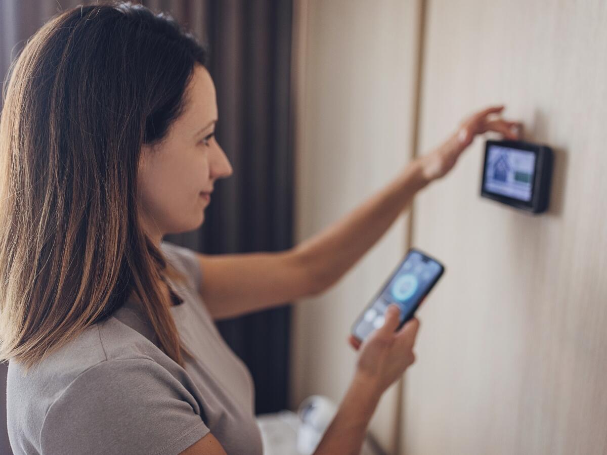 A person synching their mobile device to a smart thermostat