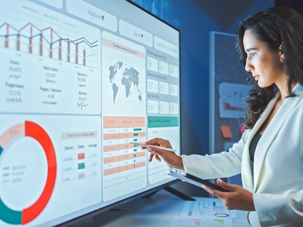 woman in lab coat entering data on large touch screen monitor