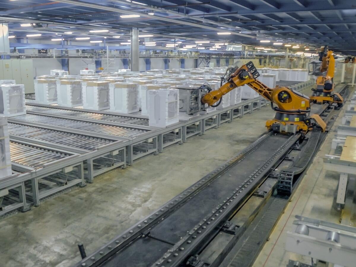 yellow robotic arms working on a production line assembling appliances