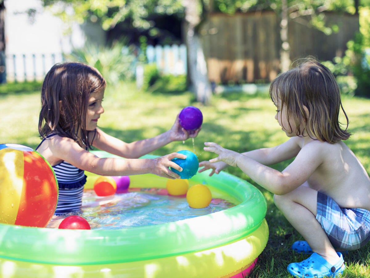 two children playing with toys in a wading pool