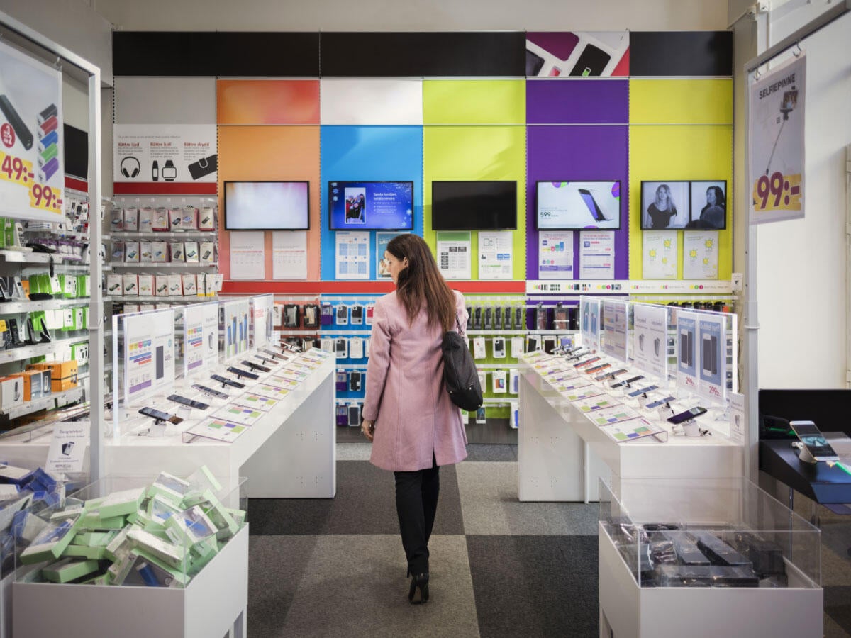 Shopper looking at mobile phones in an electronics aisle in a store