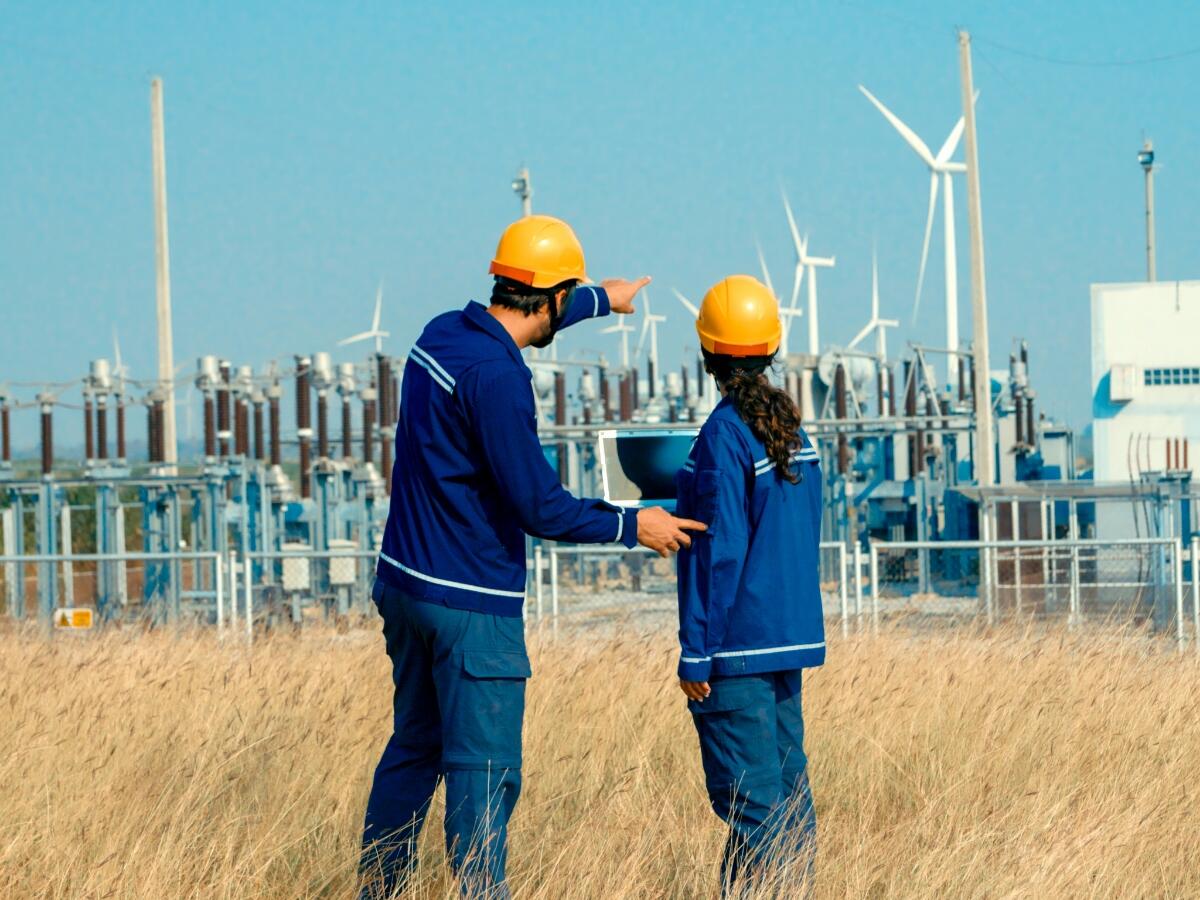 Two people working near an electrical grid
