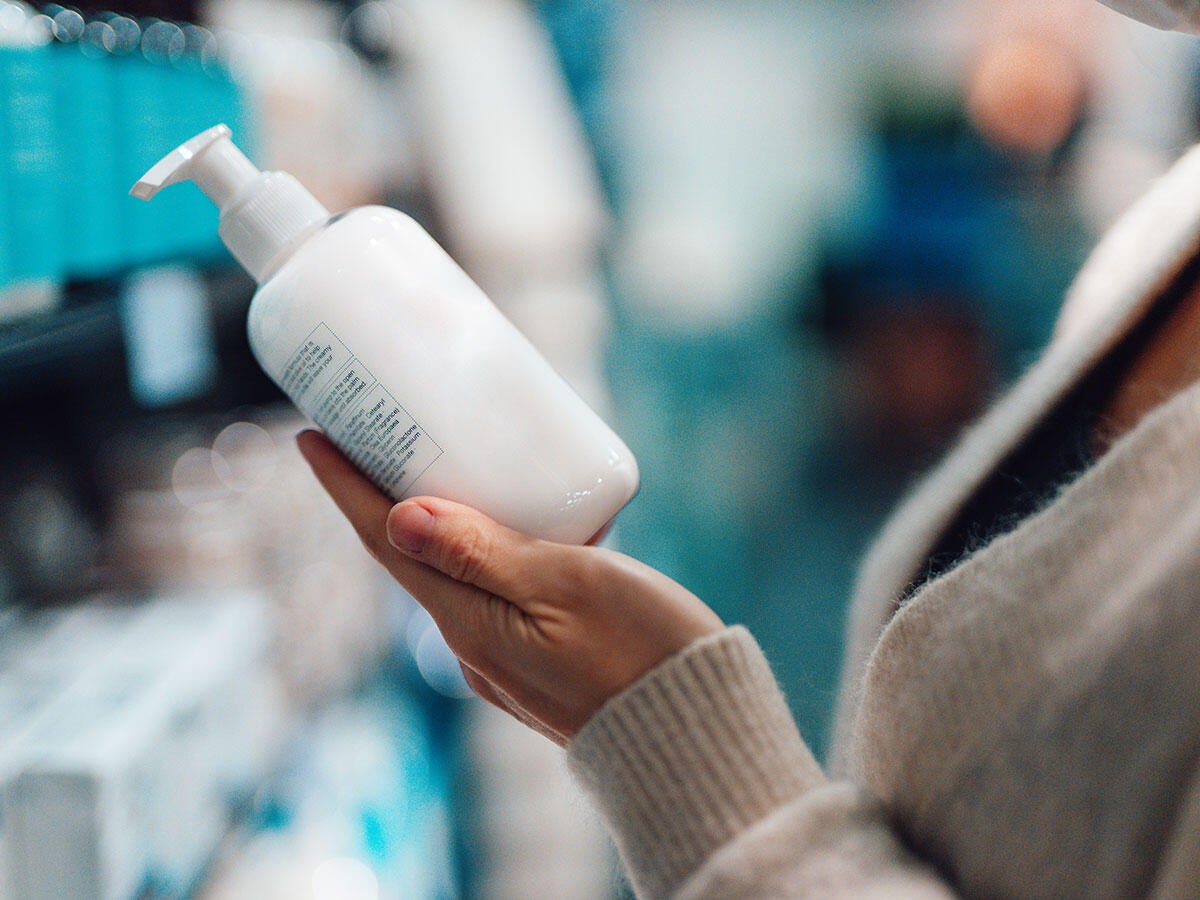 Person reading the label on a bottle of hand soap while shopping in a store