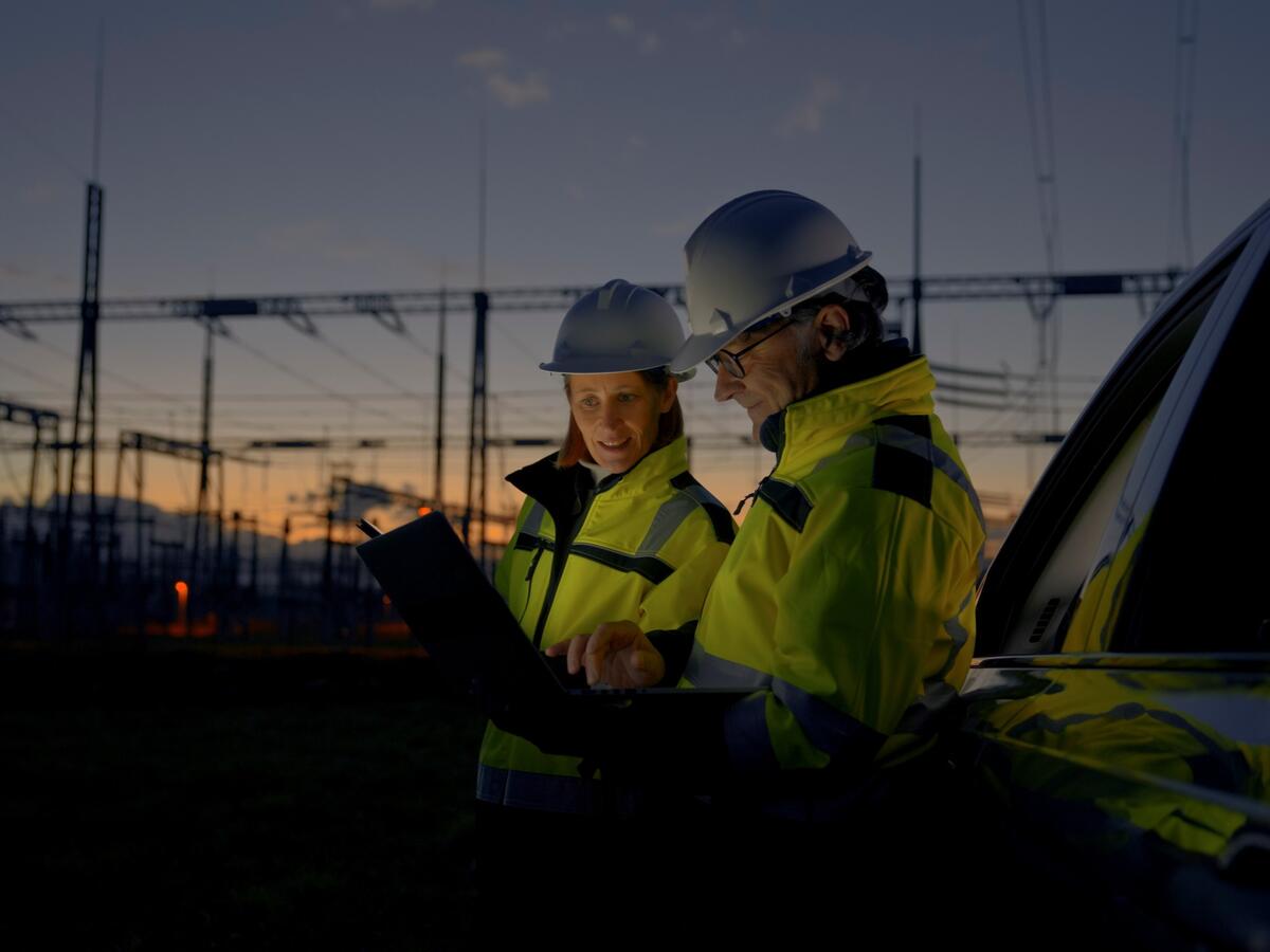 Two engineers looking at reports near a power grid.