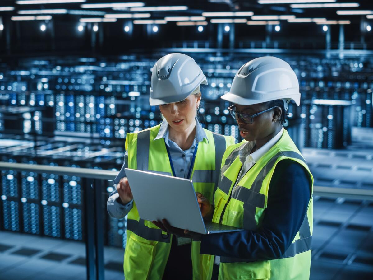 Workers looking at a laptop in a data center.