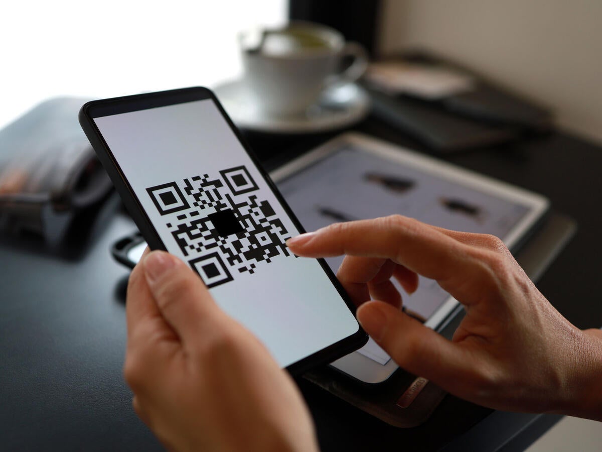 A person tapping on a QR code on a tablet screen