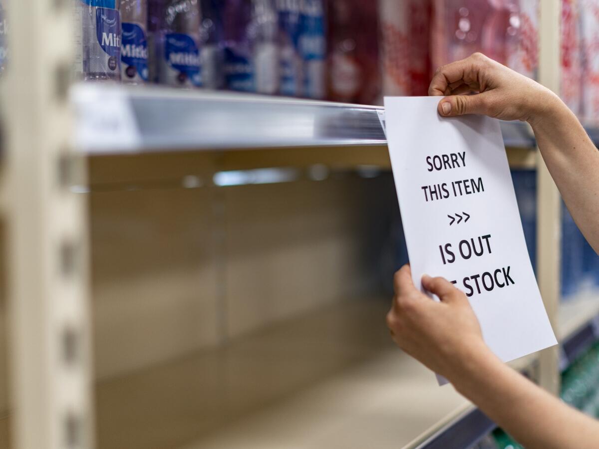 Person hanging a sign on a shelf to notify customers that a product is out of stock