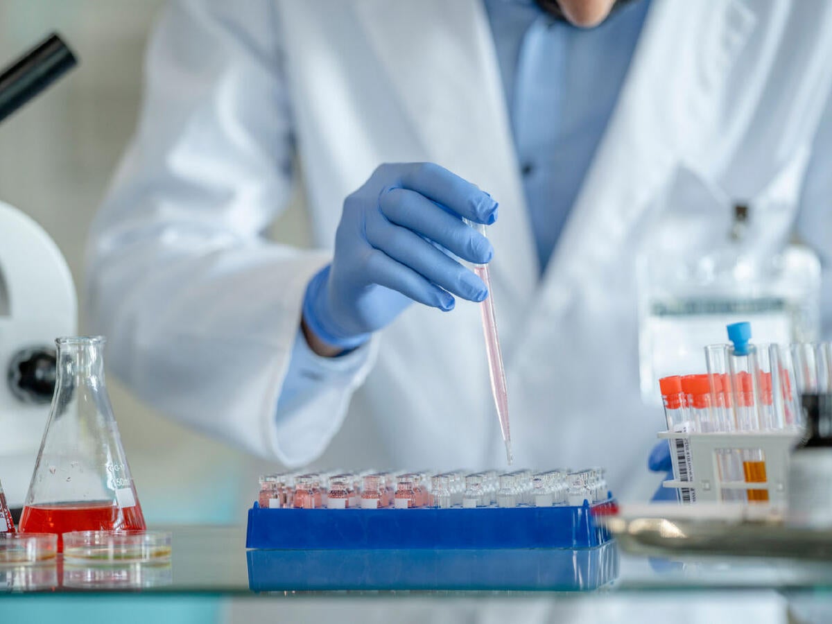 A laboratory technician dropping fluid into test tubes