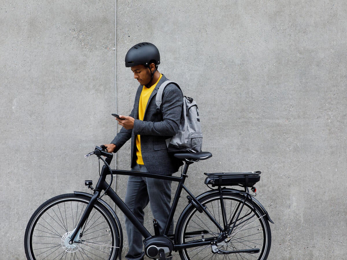 Person standing next to an electric bike looking at a phone.