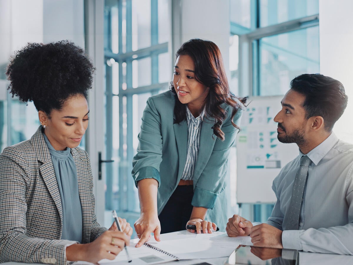 two women and man in business casual attire working at table in nicely lit office