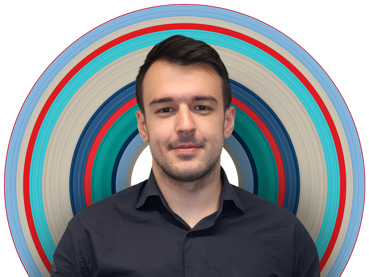 Engineer Kivanc faces the camera, smiling. He is in a dark button up shirt with dark hair. He has a stubbly beard. The background of the image is a colourful circle of potential.