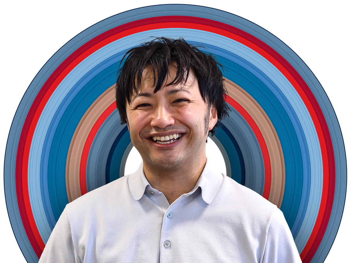 Engineer Shoma Nakanishi faces the camera with a wide smile. He has dark hair and is wearing a buttoned up shirt with the collar undone. The background features UL Solutions' Circle of Potential.