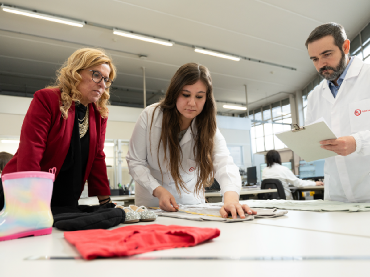 Lab techs meeting over work table examining textiles.