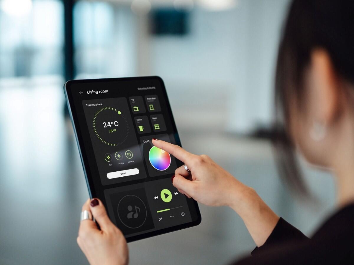 Person using a tablet device to control smart home technologies.