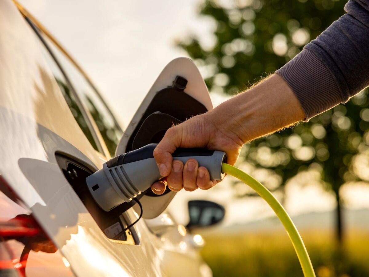 Person plugging a charger into an electric vehicle.