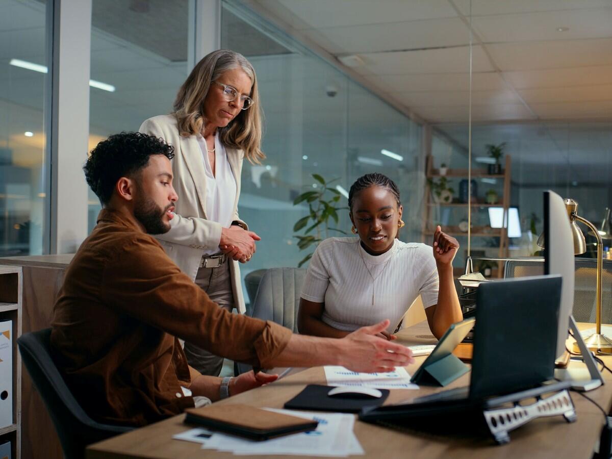 Three people in an office looking at a computer.