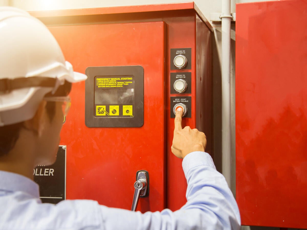 man with hardhat pushing stop button on machine