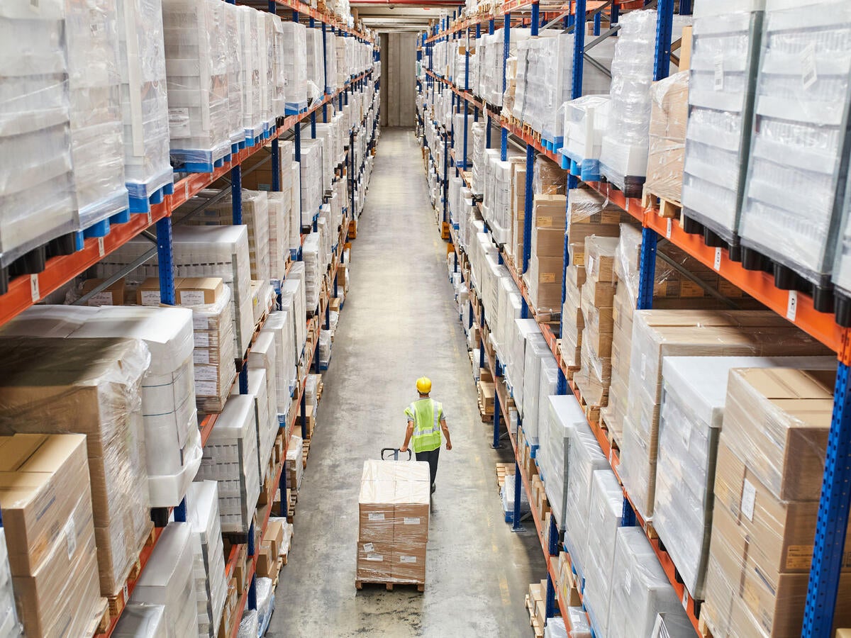 Worker in a warehouse with dozens of boxes on tall shelves