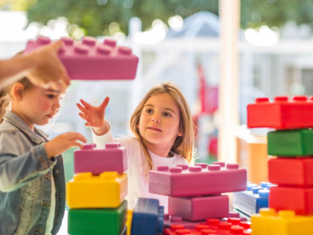 Two young children playing with foam building blocks outdoors 