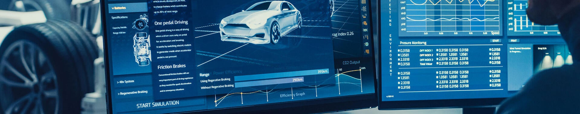 Automotive engineer looking at a computer displaying a 3D electric car chassis prototype with wheels.