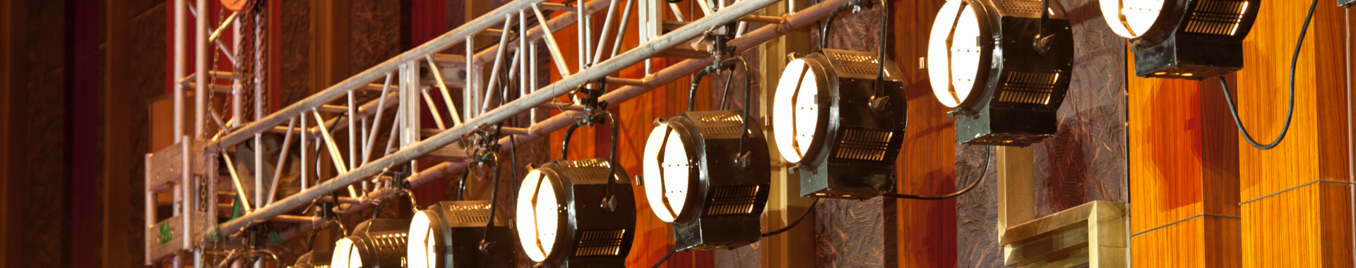 Theater lights hang from backstage scaffolding, ready for the upcoming performance. 