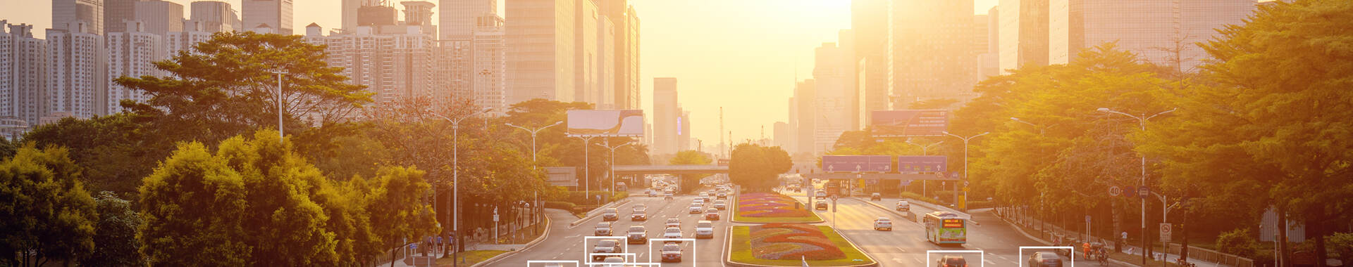 Cars highlighted by artificial intelligence driving down highway with high-rise buildings in the distance