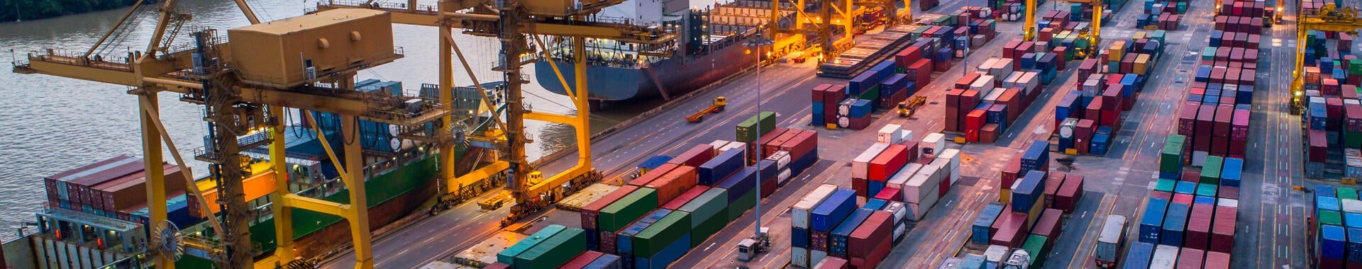 Container cargo ship and cargo plane with working crane bridge in shipyard at sunrise
