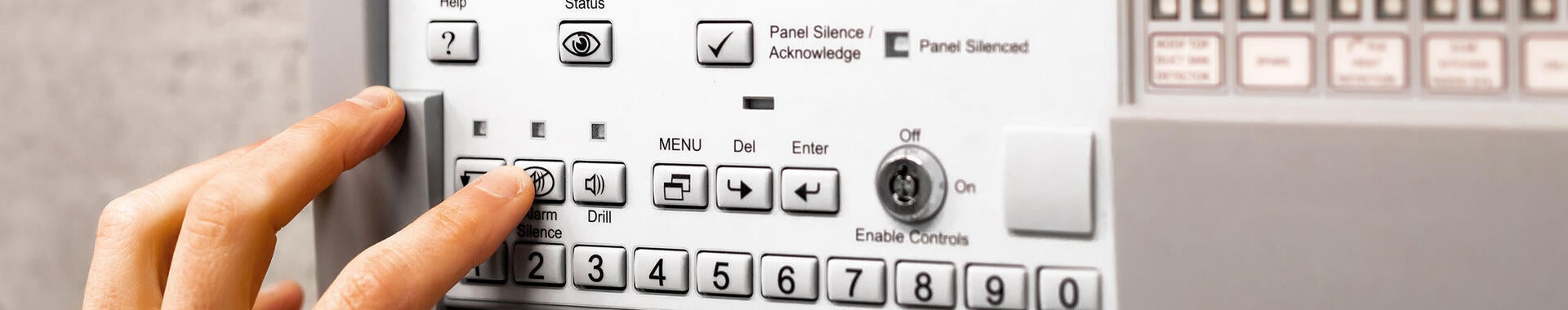 A person's hand pushing buttons on a fire detection system